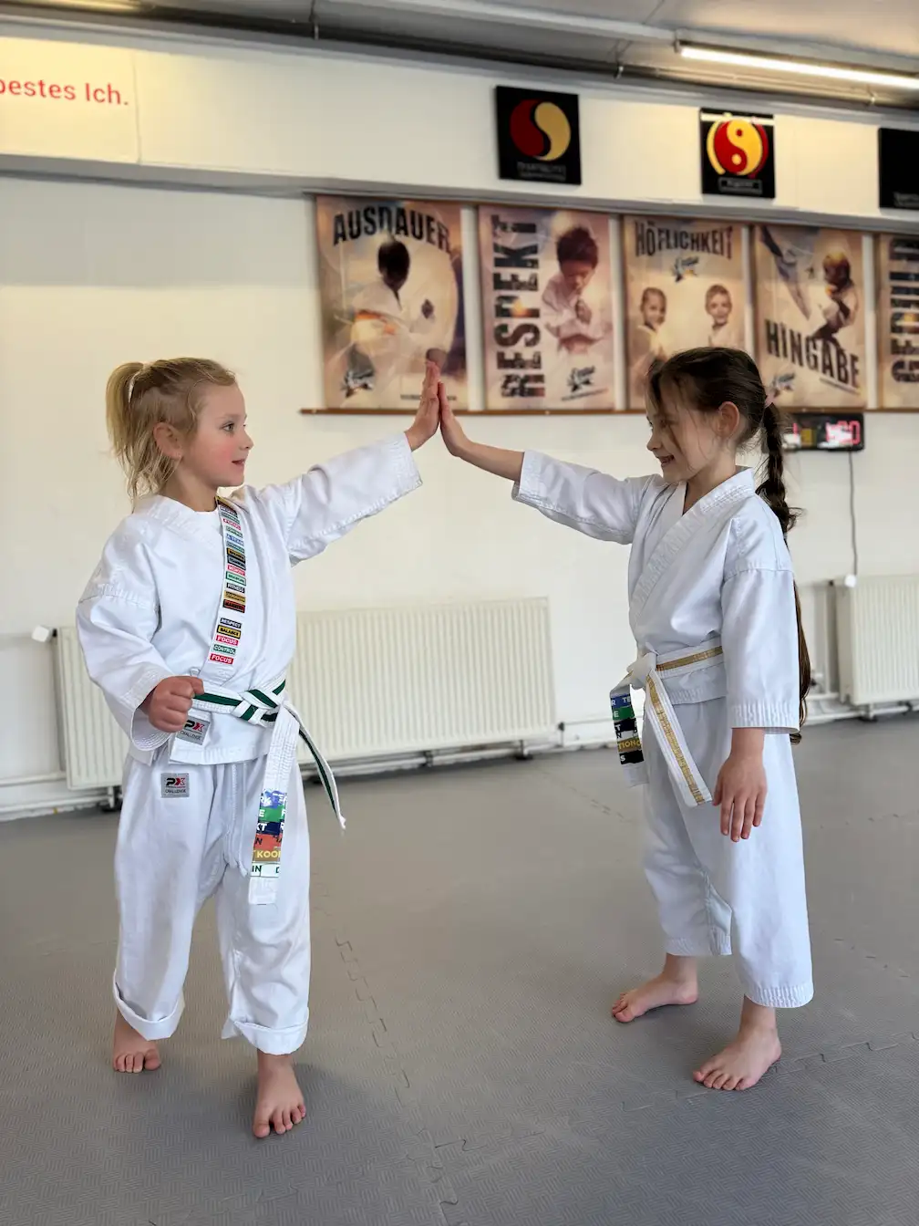 INSPIRE HEROES – Kinder im weißen Gi geben sich High-Five nach dem Unterricht